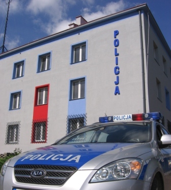 Radiowóz na tle budynku biurowego Komendy Powiatowej Policji w Proszowicach